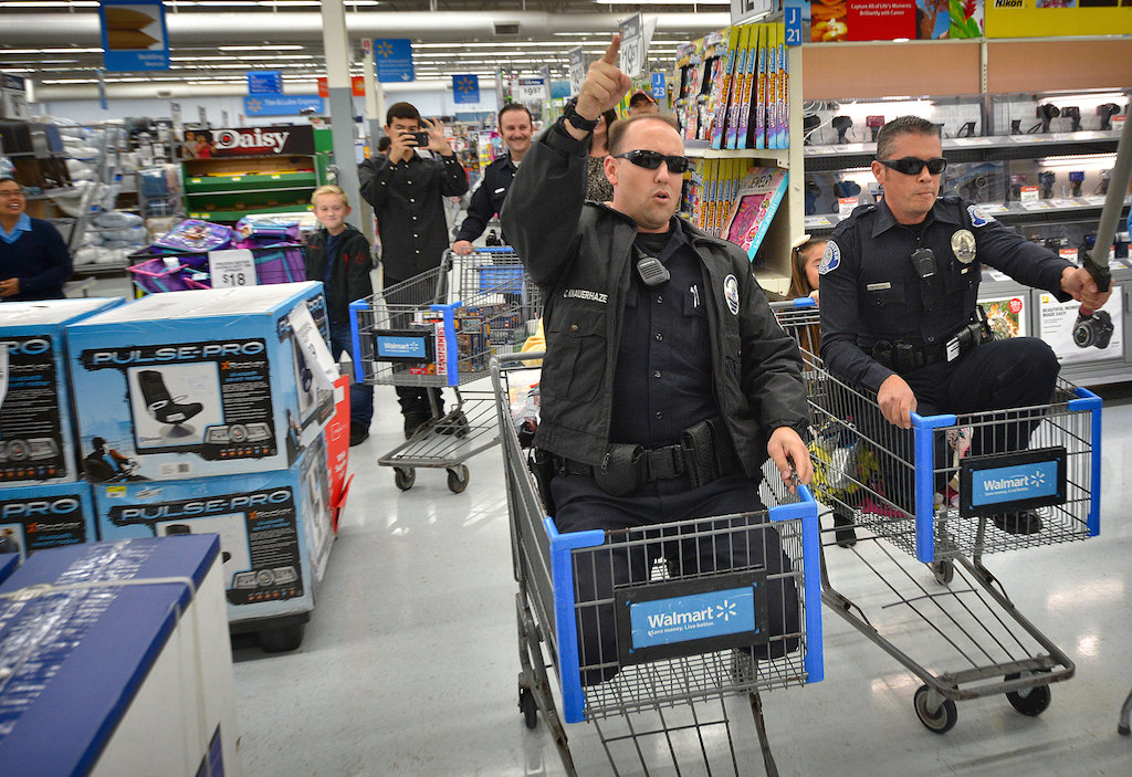Sgt. Cameron Knauerhaze of the Westminster Police Department, left, and Officer Paul Walker have a friendly race pushed by the kids they are helping during a Shop with a Cop event at a Walmart in Westminster. Photo by Steven Georges/Behind the Badge OC