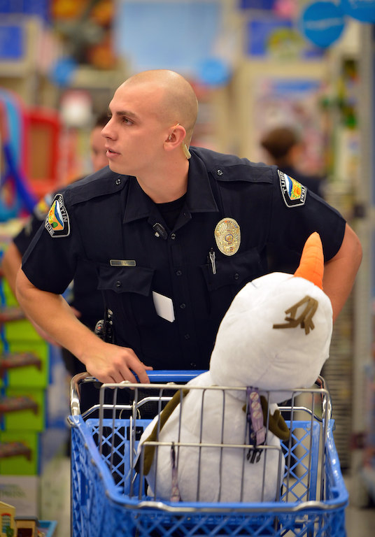 Tustin Police Officer Chris Natividad walks the aisles of Toys R Us in Tustin with a larg “Olaf” from Disney’s Frozen as Tustin PD officers who recently graduated from Golden West Police Academy take their leftover funds from their dues and by $1,700 of toys for CHOC kids. Photo by Steven Georges/Behind the Badge OC