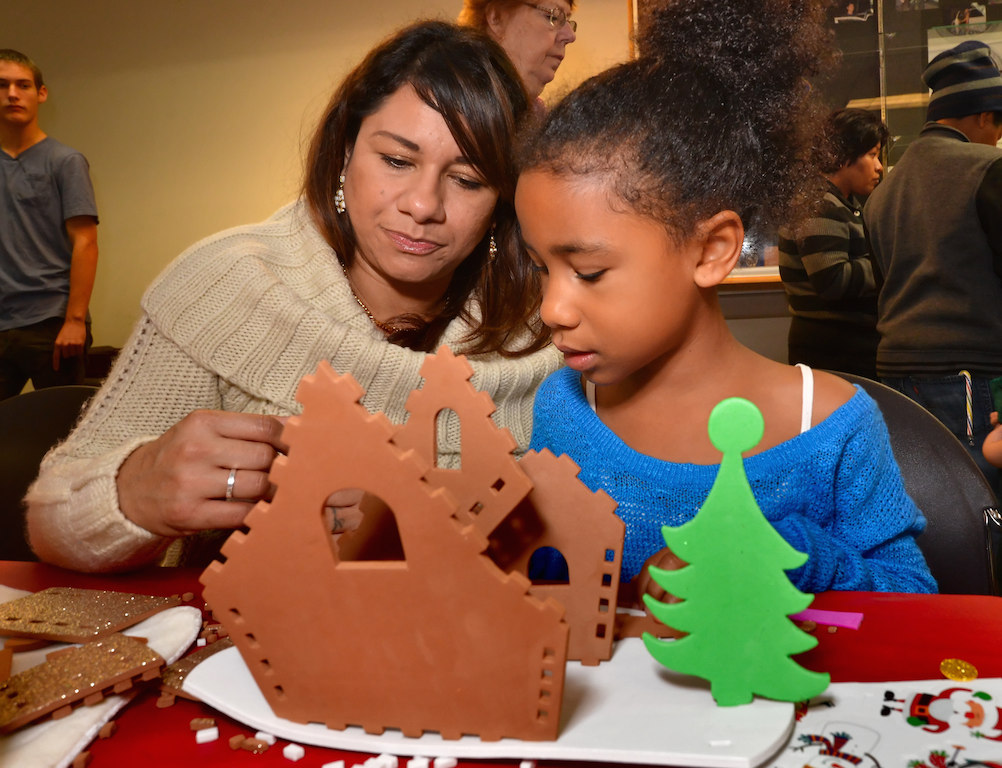 Ivonne Rosales of Fullerton works on putting together a Christmas house with her 7-year-old daughter Keilah Livingston. Photo by Steven Georges/Behind the Badge OC
