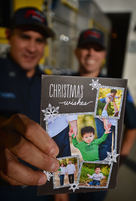 Fire Captain Tony Acosta, left, and Paramedic Ryan Van Wie, both of the Garden Grove Fire Department, hold up a Christmas card given to them by the parents of 1-year-old Caleb. Photo by Steven Georges/Behind the Badge OC