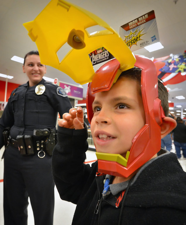 Eight-year-old Samuel Lozano tries out an Iron Man helmet with Cypress Detective Deanna Alvis behind him during a Shop with a Cop event at the Target store in Cypress. Photo by Steven Georges/Behind the Badge OC