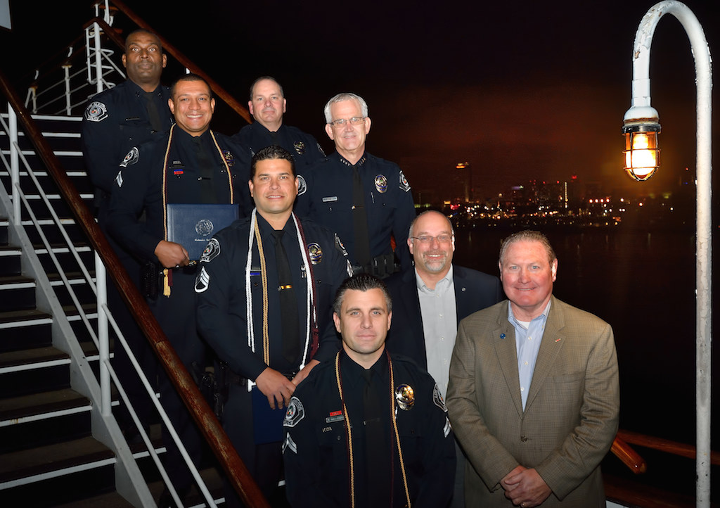 Three Los Alamitos PD graduates from Columbia College, front left, stand with representatives from Los Alamitos PD and Columbia College during a small ceremony on board the Queen Mary in recognition of completing their degree in October.  Left row, Captain Bruce McAlpine, top left, Corporal Chris Andersen, Sgt. Chris Karrer and Corporal Kain Gallaugher. Right row, Sgt. Tom Raso, top right, Chief Todd Matters, Dr. Scott Dalrymple, president of Columbia College, and Carl David, director of the Los Alamitos Campus of Columbia College. Photo by Steven Georges/Behind the Badge OC