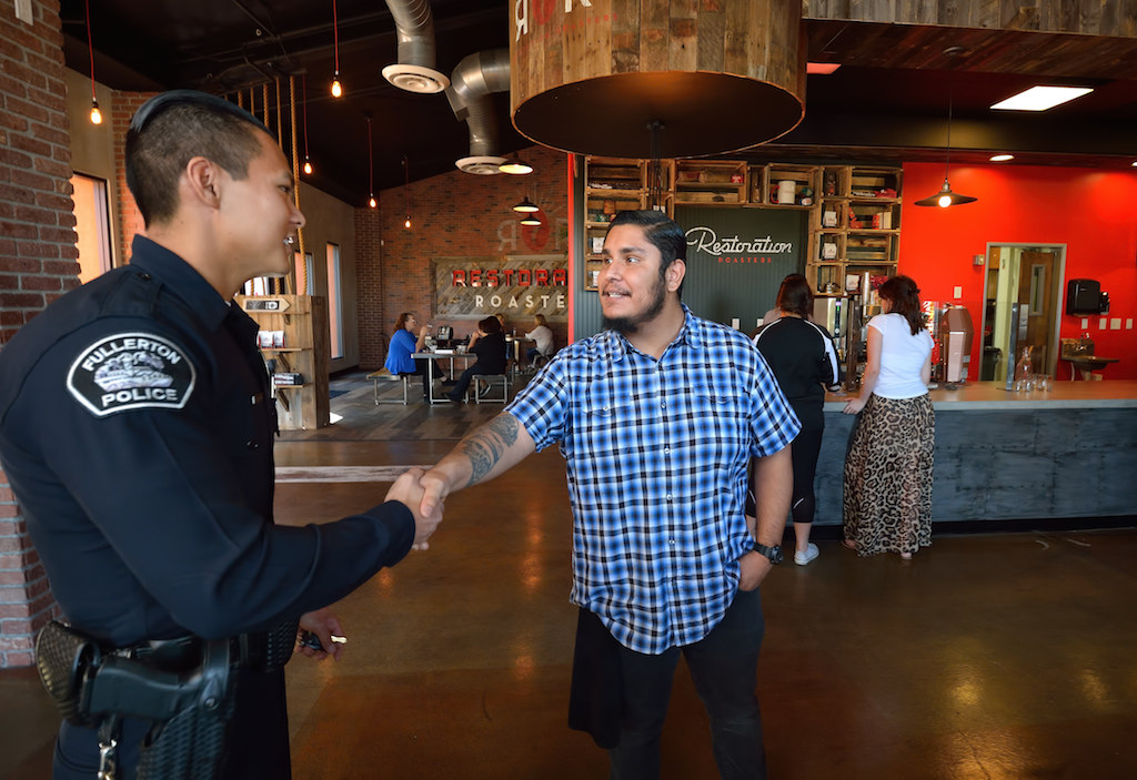 Fullerton Police Officer Denny Bak meets with Raul Perez at Restoration Roasters in Corona where Perez now works. Perez credits Officer Bak, who arrested him a year earlier, with helping him turn away from a life of drugs. Photo by Steven Georges/Behind the Badge OC