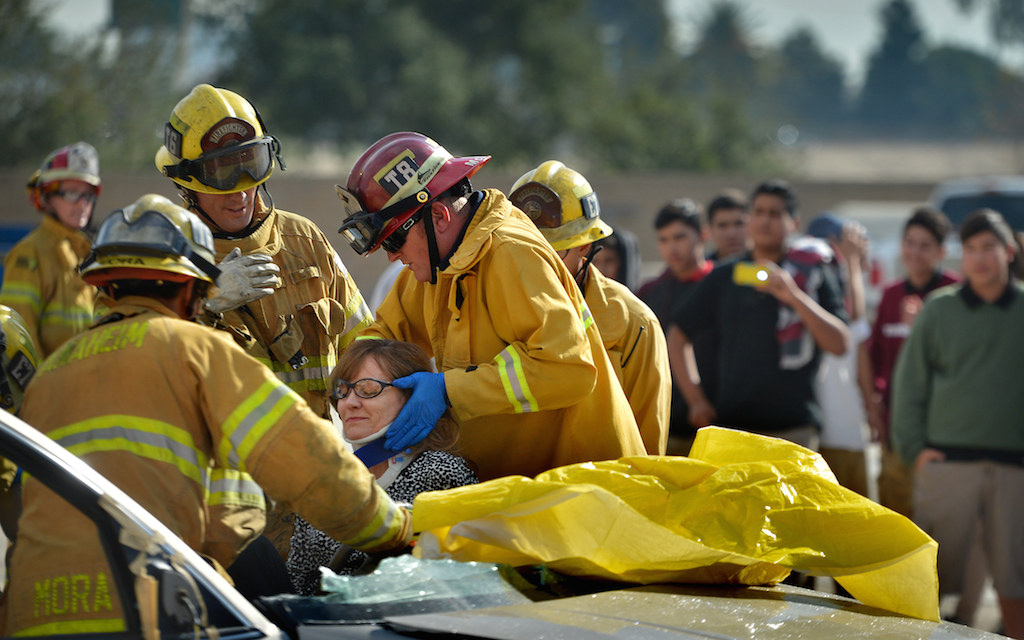 Anaheim Fire & Rescue firefighters remove volunteer Dayna Whitman, a technology at for Sycamore Jr. High, from a car after using the jaws of life during a demonstration as her students watch. Photo by Steven Georges/Behind the Badge OC
