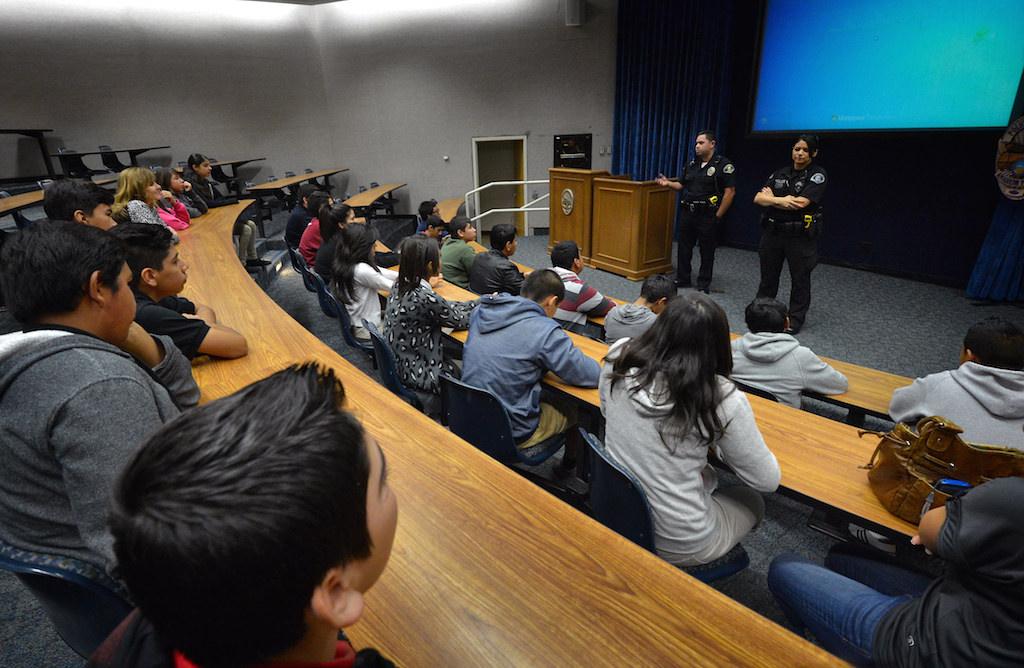 Anaheim Police Officer William Martinez, left, and Investigator Flora Palma talk to a group of kids from Sycamore Jr. High gathered in a briefing room Jan. 7. Photo by Steven Georges/Behind the Badge OC