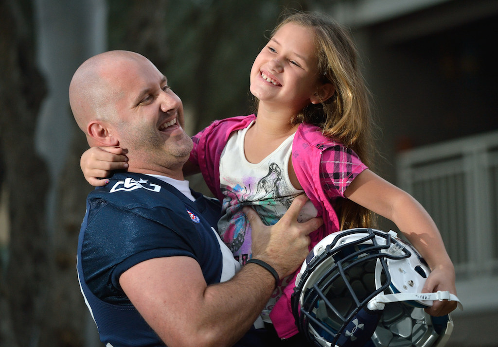 Officer Tommy Mellana of the Cypress PD with his 7-year-old daughter Aubree Mellana. Officer Mellana plays with the football team Orange County Lawmen, law enforcement personnel, firefighters, public safety employees (and limited number of civilians) that volunteer their time playing to raise money for charities. Photo by Steven Georges/Behind the Badge OC