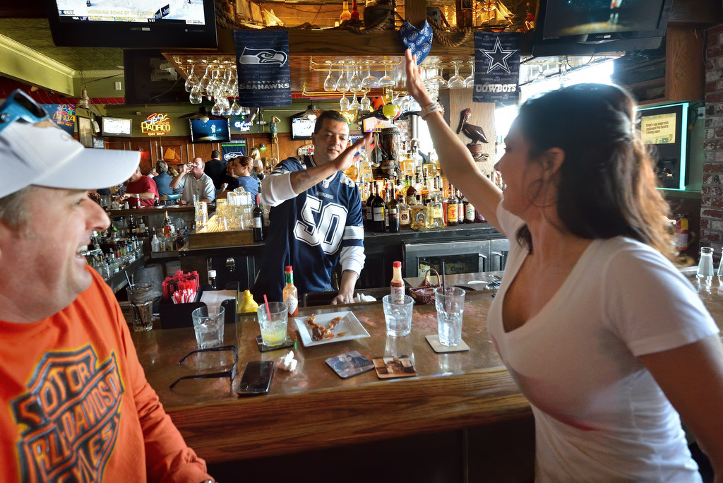 Lisa Langdon of Sunset Beach, who walked to Pelican Isle in Sunset Beach with her husband Dean Langdon, left, gives Bartender Luis Byllaser a high five after passing a voluntary sobriety test given by a Huntington Beach police officer as part of a public awareness campaign. Photo by Steven Georges/Behind the Badge OC