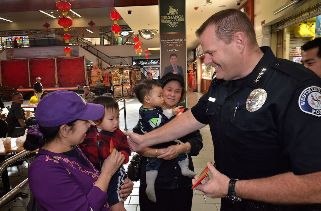 Westminster Police Chief Kevin Baker introduces himself to Thu Tran and her 16-month-old grandson Liem Vu during a visit to the Asian Garden Mall in Westminster’s Little Saigon. Behind them is Lieu Nguyen holding her grandson 12-month-old Westley Nguyen. Photo by Steven Georges/Behind the Badge OC
