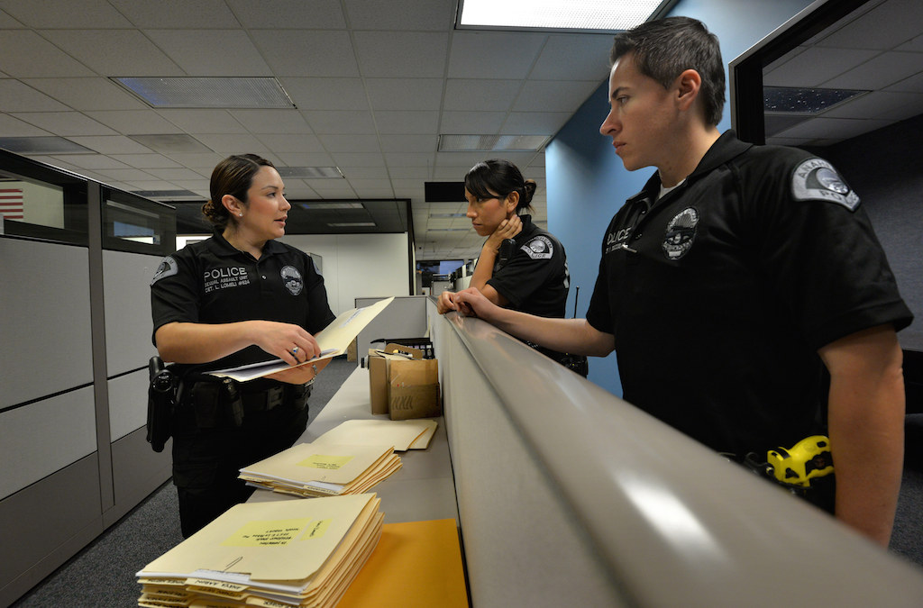 Det. Laura Lomeli of the Anaheim Police Department’s Sexual Assault Detail (left) goes over the cases of convected sex offenders they need to visit that day with Officer Ledy Carla Cashell, on loan from the Safe Schools Gang Intervention detail, and Officer Yesenia Escobar, right. Photo by Steven Georges/Behind the Badge OC