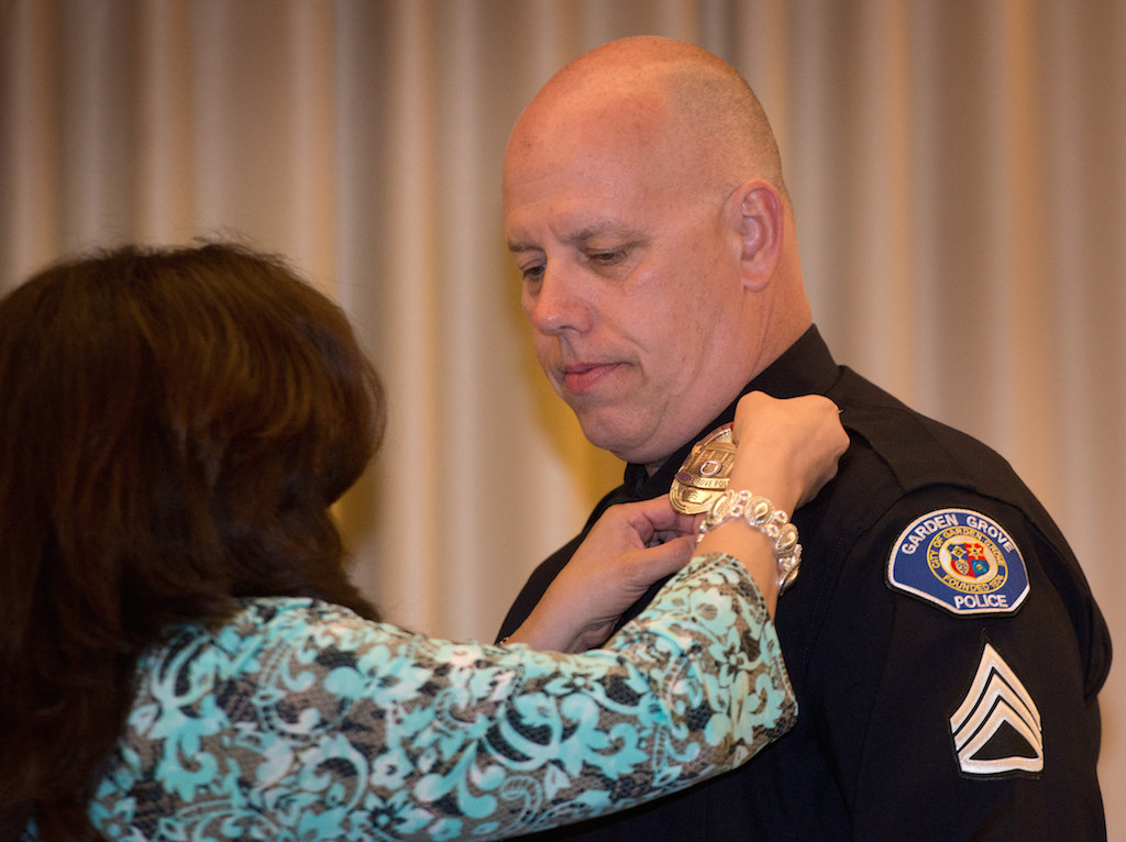 Sgt. Philip Schmidt gets his new badge pinned to him by his wife. Photo: Steven Georges