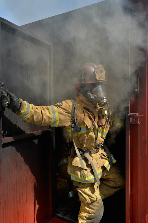 Captain Tim Sandifer of Anaheim Fire & Rescue closes the door of a customized shipping container with his fellow fighters inside while a fire burns inside during a training exercise at the North Net Fire Training center in Anaheim. Photo by Steven Georges/Behind the Badge OC