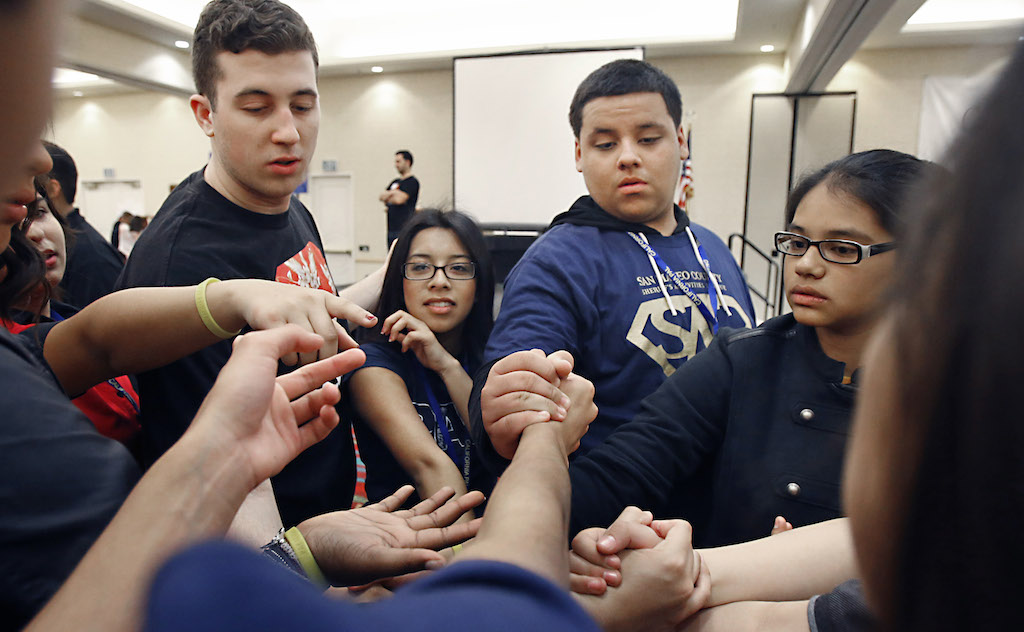 Los estudiantes participaron en una actividad en la que tratan de salirse del nudo sin soltarse de las manos.  Fotografía por Christine Cotter/Behind the Badge OC 