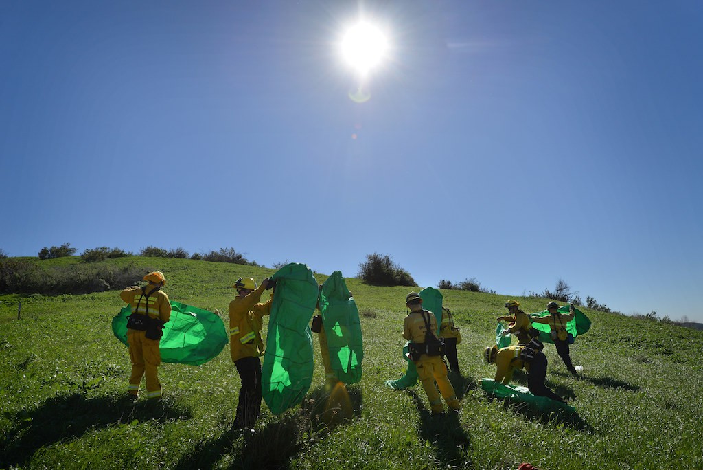 Firefighters from Anaheim, Garden Grove and Orange use practice personal fire shelters to cover themselves during a training exercise at Santiago Oaks Regional Park. Practice tarps are used do to the expense of using real ones. Photo by Steven Georges/Behind the Badge OC