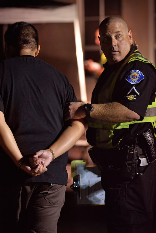 Officer Nathan Morton of the Garden Grove PD takes a suspected drunk driver into custody during a Garden Grove PD DUI checkpoint on Chapman Ave. Photo by Steven Georges/Behind the Badge OC