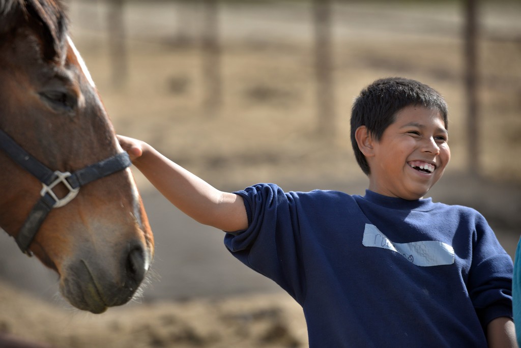 Eleven-year-old Alexis of Huntington Beach smiles as he interacts with one of the horses at Huntington Central Park Equestrian Center. The afternoon is part of a 10-week program for students from Oak View Elementary School sponsored by the Huntington Beach PD and the Rainbow Environmental Services. Photo by Steven Georges/Behind the Badge OC