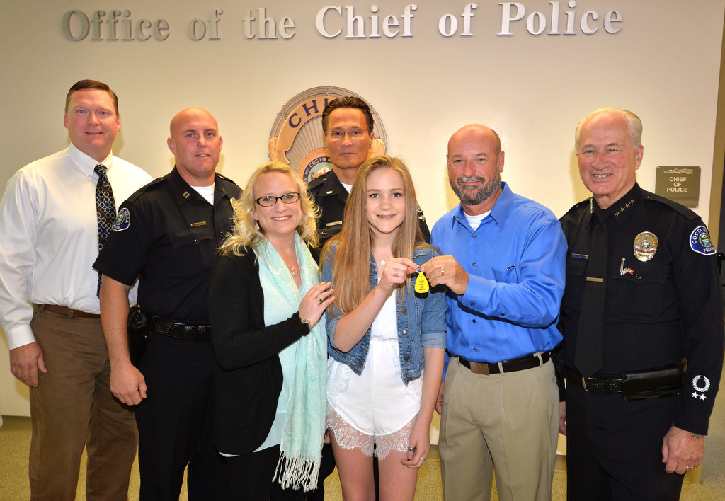Haley Farnsworth, 15, center, holds her nine-month sobriety chip as she stands next to her mother Danielle Farnsworth, Sgt. Tom Starn, now retired, right of her, and Interim Police Chief Ron Lowenberg, far right, as Haley came to thank the Costa Mesa PD for saving her from jumping from a freeway overpass about year ago. Photo by Steven Georges/Behind the Badge OC