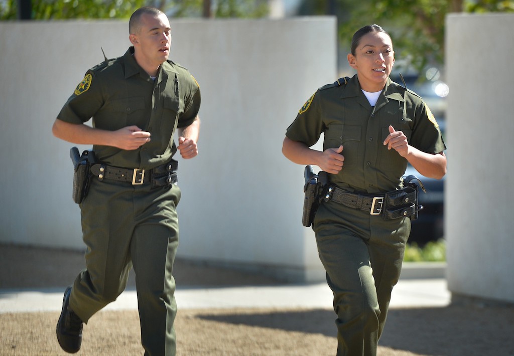 Orange County Sheriff Recruits Zachary Vanden Bosch, left, and partner Margarita Alatore chase a suspect during the Will to Survive test at the OC Sheriff Training Academy in Tustin. The recruits run through the test as a team of two helping the other out if needed. Photo by Steven Georges/Behind the Badge OC