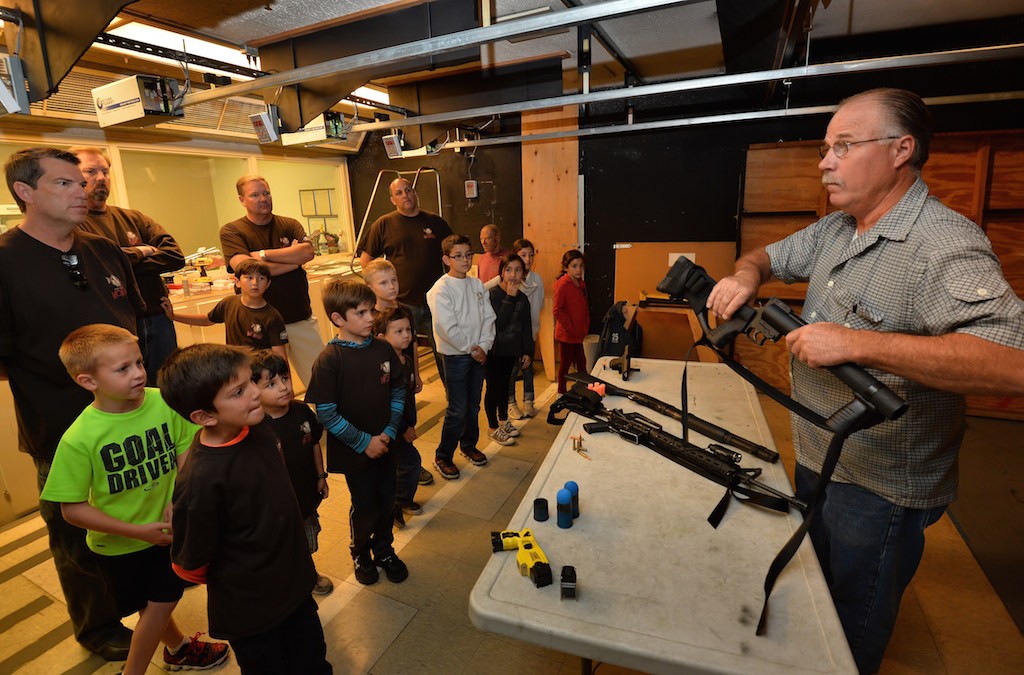 Fullerton PD Range Master Dave Benedict shows kids from YMCA’s Adventure Guides various types of weapons, including less lethal weapons, as they visit the Fullerton PD gun range, part of a tour of the police department. Photo by Steven Georges/Behind the Badge OC