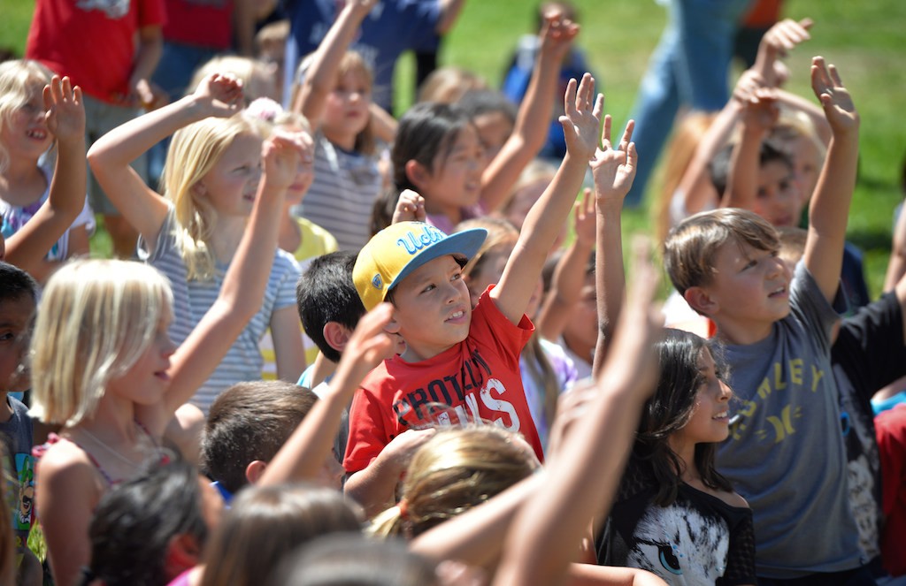 Kids from Rolling Hills Elementary School raise their hands to volunteer as members of the Fullerton Police and Fire Departments visit the school during a Team Kids assembly. Photo by Steven Georges/Behind the Badge OC