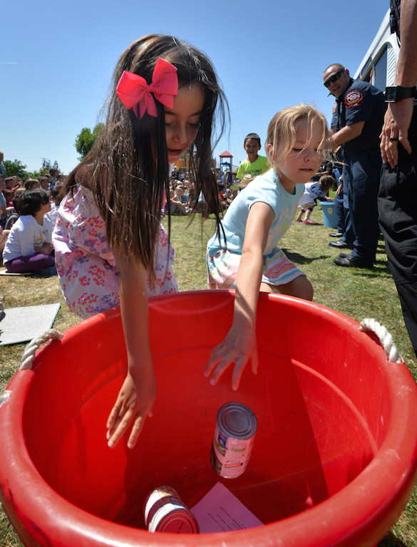 Kids from Rolling Hills Elementary School in Fullerton fill a bucket with can food during a demonstration relay that was part of a Team Kids assembly at the school. Photo by Steven Georges/Behind the Badge OC