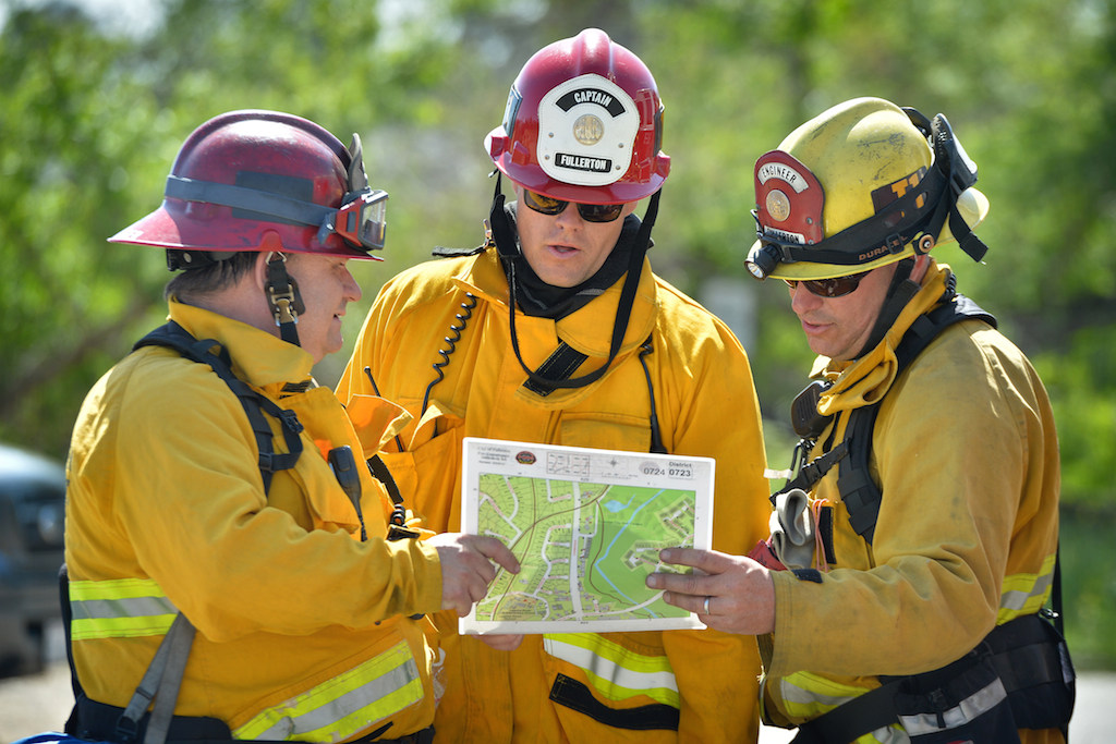 Captain Harbinger, left, Captain Nigg and Engineer Zeller of the Fullerton Fire Department plan their next move after a vegetation fire that broke out in the Brea Dam Recreation Area Saturday afternoon threatening homes in the area. Photo by Steven Georges/Behind the Badge OC