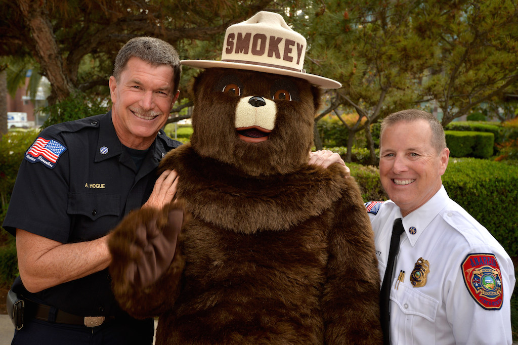 Capt. Allen Hogue of Anaheim Fire & Rescue, left, with Smokey Bear and Anaheim Fire Marshal Jeff Lutz after after they received a proclamation from the Anaheim City Council about Wildfire Awareness Week. Photo by Steven Georges/Behind the Badge OC