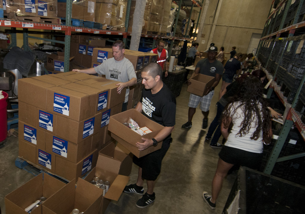 Shonn Rojas, center, and other members of Tustin Police Department, package canned goods for the needy as part of the organizations' community outreach efforts at the OC Rescue Mission in Tustin.  Photo by Carlos Delgado/Behind the Badge OC