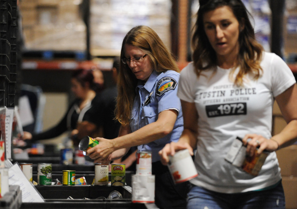 Trish Jansen, left, and Brittany Jensen, of the Tustin Police Department, package canned goods for the needy as part of the organizations' community outreach efforts at the OC Rescue Mission in Tustin.  Photo by Carlos Delgado/Behind the Badge OC