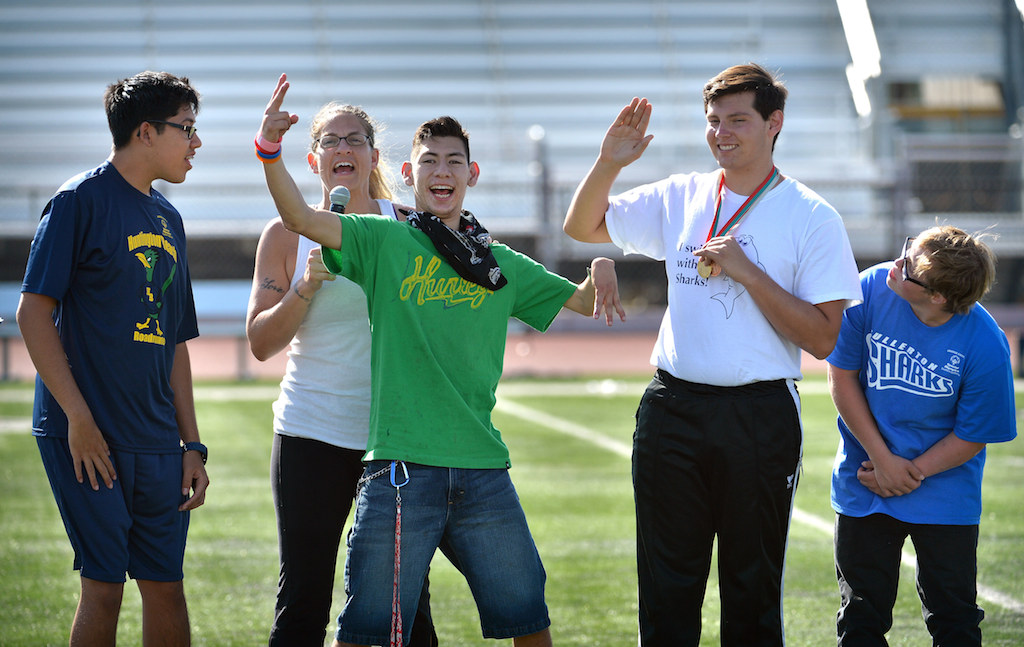 Mark Woffler II, left, Christian Andrade, Christian Valdez and Cole Sibus wave to the crowd at the start of the halftime kicking competition of Freedom Bowl II benefiting Special Olympics Southern California. Photo by Steven Georges/Behind the Badge OC