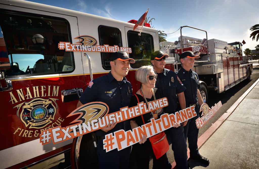 Anaheim Ducks fan (and now Anaheim Fire & Rescue fan) Chris Shedlowski of Anaheim has her photo taken with Paul Erskine, left, Rick Romero and Don Hail of Anaheim Fire & Rescue as she arrives for the Ducks playoff game at the Honda Center. Shedlowski has been coming to watch the Ducks for the past 21 years, since the team was created. Photo by Steven Georges/Behind the Badge OC