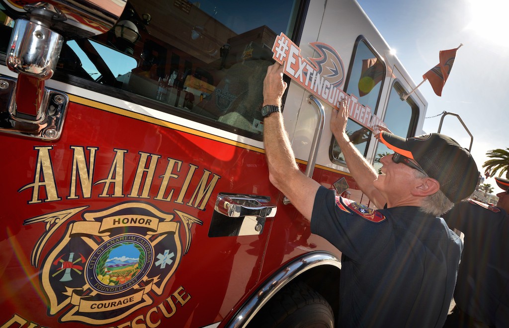 Captain Don Hail of Anaheim Fire & Rescue place “Extinguish The Flames” signs on Anaheim’s Truck 6 while fans arrive at the Honda Center for Game 1 of the second-round NHL series as the Anaheim Ducks host the Calgary Flames. Photo by Steven Georges/Behind the Badge OC