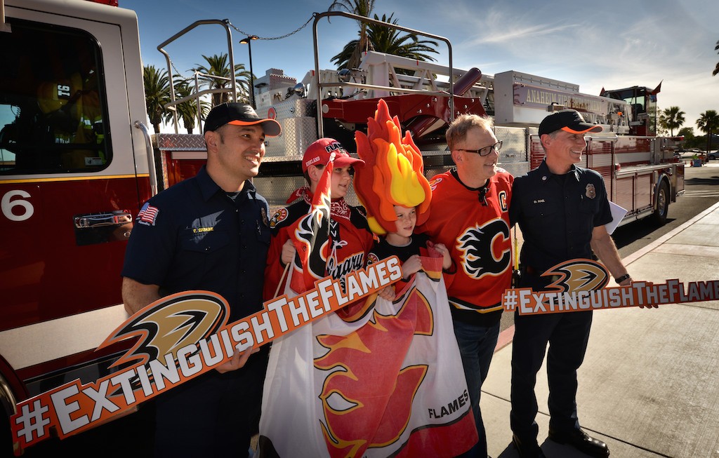 Firefighter Paul Erskine, left, and Captain Don Hail of Anaheim Fire & Rescue show their hospitality to Calgary Flames fans Kirkland Sternberg, 13, left, his cousin Brock Sikorsky, 11, and his father Ryan Sikorsky, all from Calgary, in front of the Honda Center before the start of Game 1 as the Anaheim Ducks host the Calgary Flames. Photo by Steven Georges/Behind the Badge OC