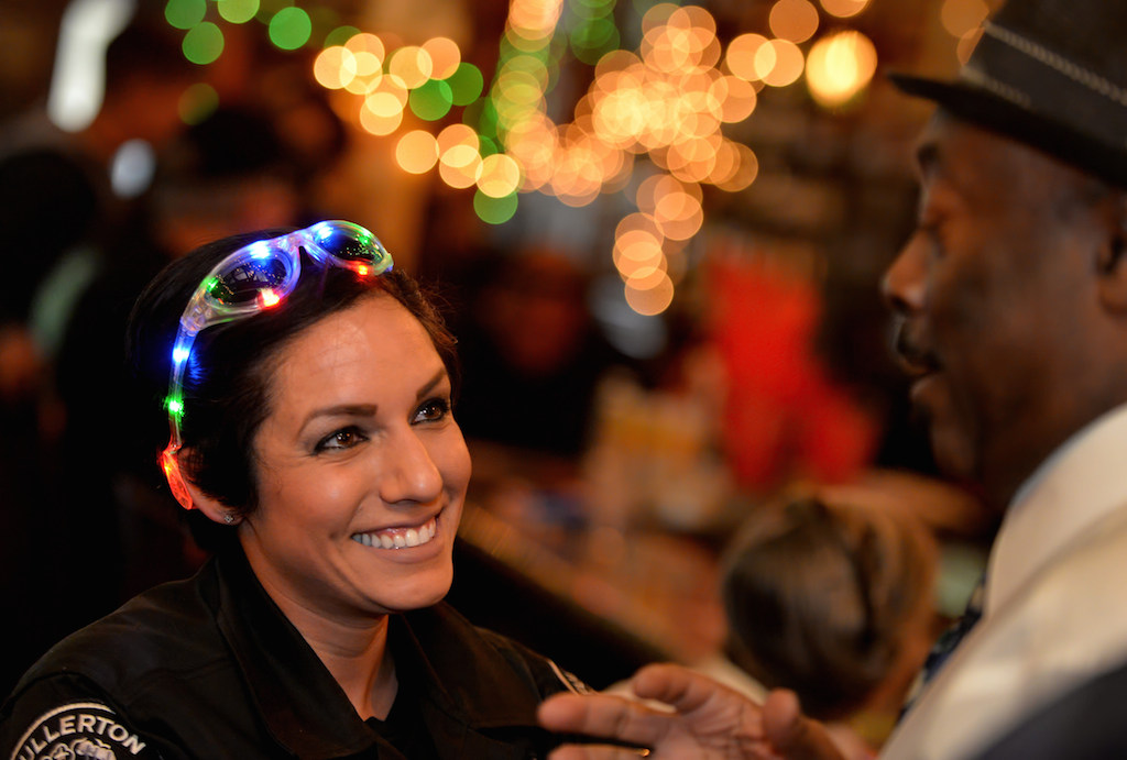 Officer Hazel Rios smiles as she is serenaded by Sam Green, right, at Heroes Bar and Grill during the Tip-A-Cop fundraiser benefiting the Athletes of Special Olympics Orange County. Photo by Steven Georges/Behind the Badge OC