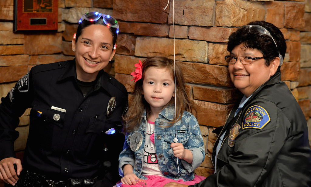 Fullerton PD Cpl. Gaby Soto, left, 4-year-old Olivia Miller of Fullerton and Juanita Juarez Fullerton PD community service officer at Heroes Bar and Grill during the Tip-A-Cop fundraiser benefiting the Athletes of Special Olympics Orange County. Photo by Steven Georges/Behind the Badge OC