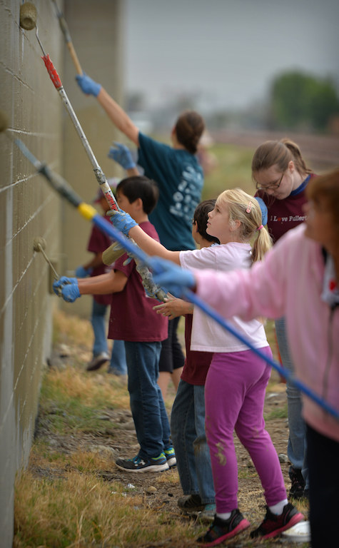 Sarah Gudmundsen, 8, from Fullerton, volunteers to help paint over graffiti on the walls along the railroad tracks during the second annual Love Fullerton community volunteer event. Photo by Steven Georges/Behind the Badge OC