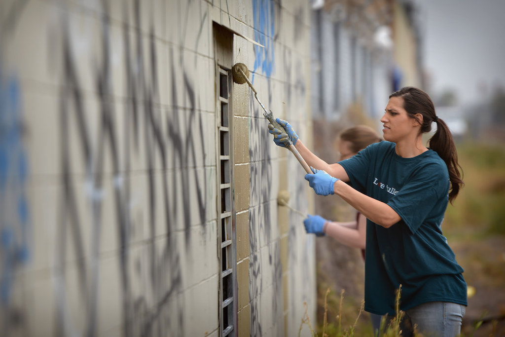 Katie Villanueva of EvFree (First Evangelical Free Church of Fullerton) paints over graffiti on the walls along the railroad tracks during the second annual Love Fullerton community volunteer event. Photo by Steven Georges/Behind the Badge OC