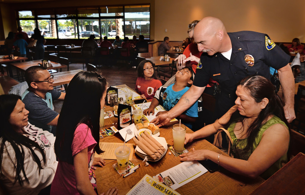 Anaheim PD Lt. James Kazakos serves food to the Avila family from Stanton during the Tip-A-Cop Tip-A-Cop fundraiser for Cops for Kids. Photo by Steven Georges/Behind the Badge OC