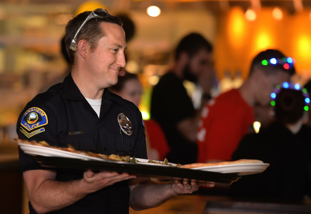 Communications Supervisor Steven Querry delivers pizza during the Tip-A-Cop Tip-A-Cop fundraiser for Anaheim PD’s Cops for Kids at California Pizza Kitchen. Photo by Steven Georges/Behind the Badge OC