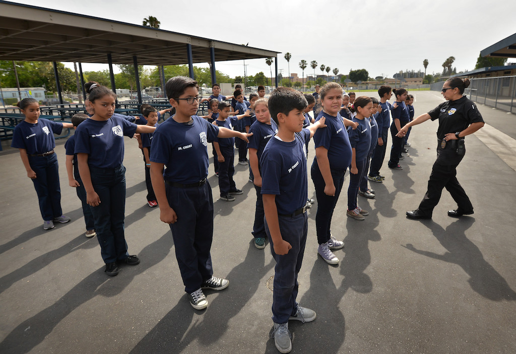 Anaheim PD Officer Leslie Vargas, right, works with Jr. Cadets on drills during an Anaheim PD Cops for Kids class at Paul Revere Elementary in Anaheim. Photo by Steven Georges/Behind the Badge OC
