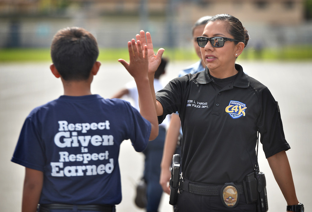 Anaheim PD Officer Leslie Vargas gives a Jr. Cadet a high-five for a job well done during an Anaheim PD Cops for Kids class at Paul Revere Elementary in Anaheim. Photo by Steven Georges/Behind the Badge OC