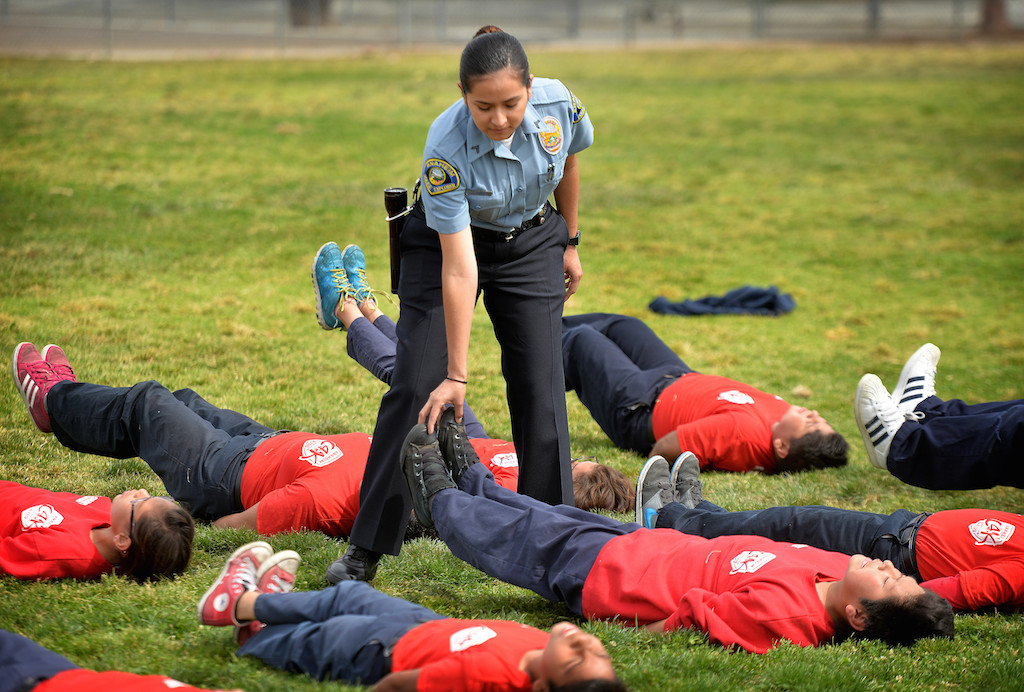 Anaheim Police Explorer Geraldi Armas helps Jr. Cadets with their technique for calisthenics during a Cops for Kids class at Paul Revere Elementary in Anaheim. Photo by Steven Georges/Behind the Badge OC