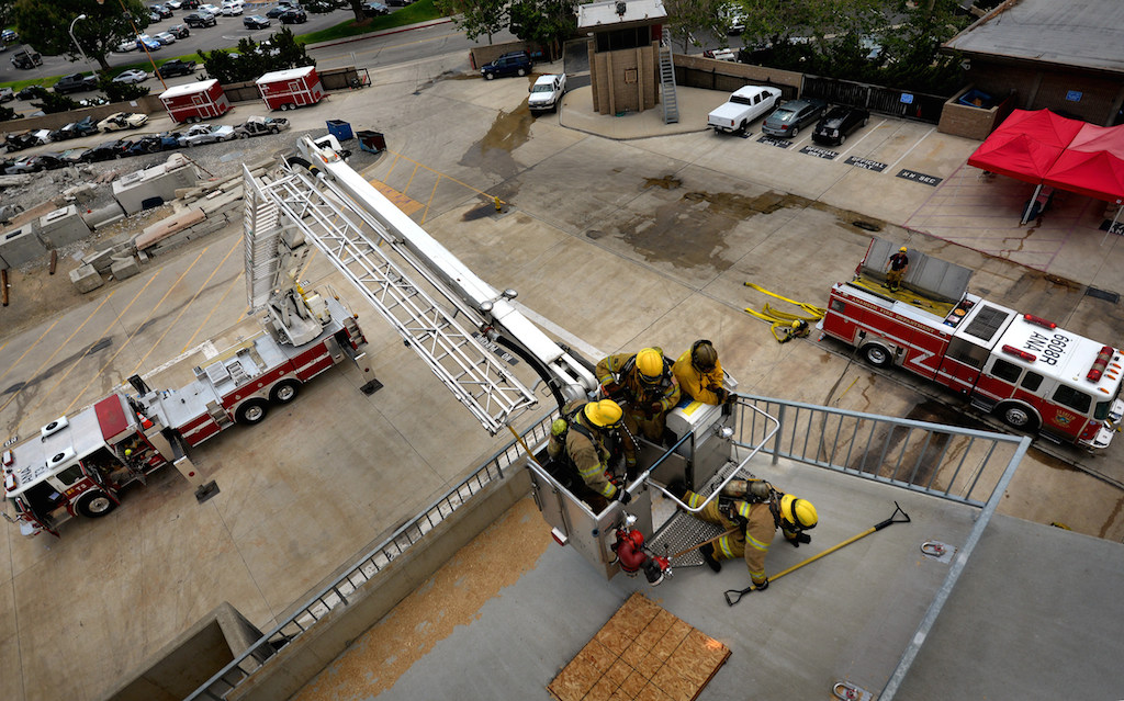 Recruit Jonathan Neu climbs onto the the North Net Training Center tower from Truck 3’s ladder as Pomerne Jones and Michael Hoover get ready to follow during a training exercise at the center. Photo by Steven Georges/Behind the Badge OC
