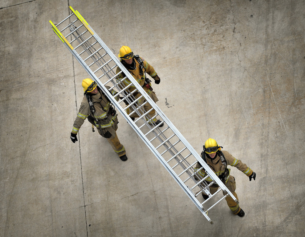 Recruits Pomerne Jones, left, Michael Hoover and Jonathan Neu carry a ladder to the North Net Training Center tower during a training exercise. Photo by Steven Georges/Behind the Badge OC