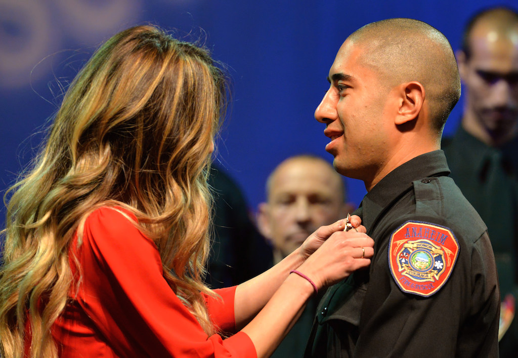 Anaheim Firefighter Calvin Bui receives his badge from his fiance Erika Jacobs during the Anaheim Fire & Rescue Promotion and Graduation ceremony. Photo by Steven Georges/Behind the Badge OC