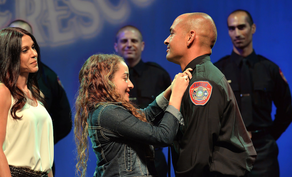 Anaheim Firefighter Pomerne Jones receives his badge from his daughter Mia Jones and his girlfriend Leslie Darby, left, during the Anaheim Fire & Rescue Promotion and Graduation ceremony. Photo by Steven Georges/Behind the Badge OC