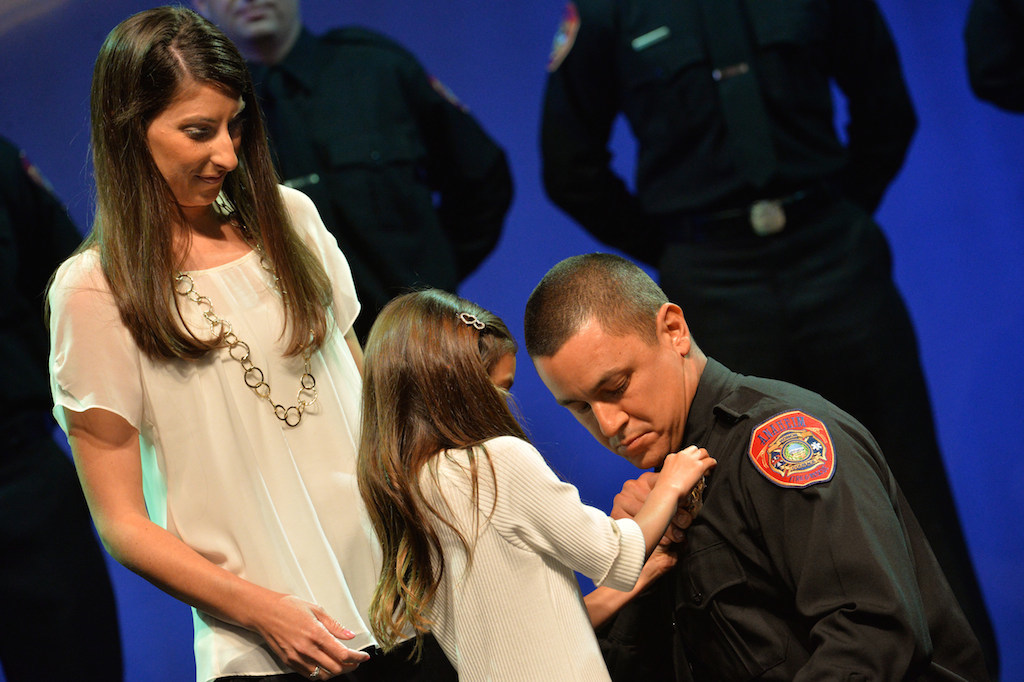 Anaheim Firefighter Erik Garcia receives his badge from his wife Vanessa and their daughter Emily during the Anaheim Fire & Rescue Promotion and Graduation ceremony. Photo by Steven Georges/Behind the Badge OC