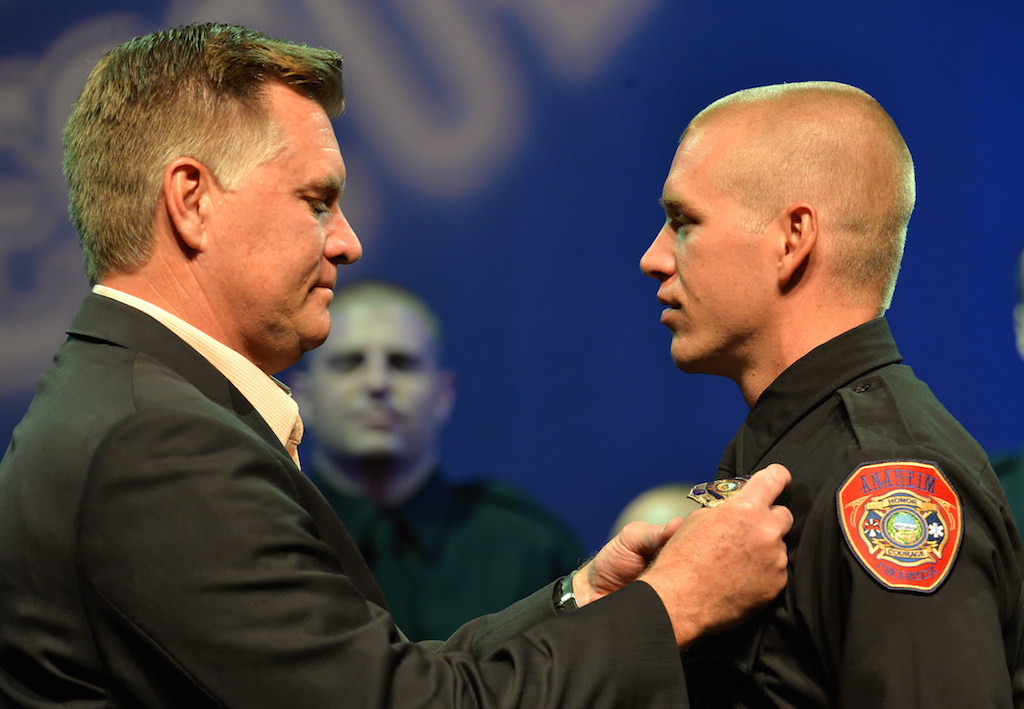 Anaheim Firefighter Blake Berg receives his badge from his father Scott Berg, retired Deputy Chief For Anaheim Fire, during the Anaheim Fire & Rescue Promotion and Graduation ceremony. Photo by Steven Georges/Behind the Badge OC