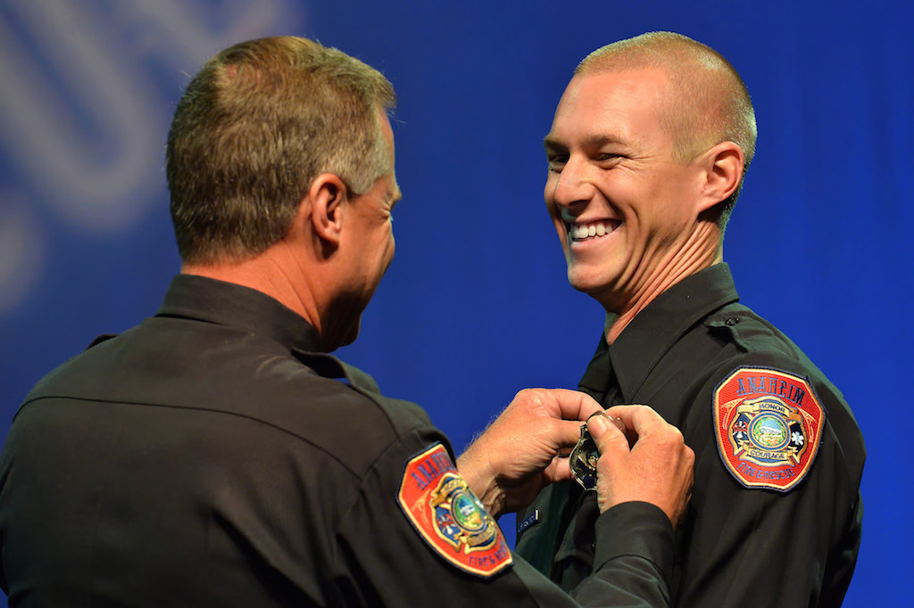 Anaheim Firefighter John Strickland Iii flashes a big smile as he receives his badge from his father, Anaheim Fire & Rescue Captain John Strickland, during the Anaheim Fire & Rescue Promotion and Graduation ceremony. Photo by Steven Georges/Behind the Badge OC