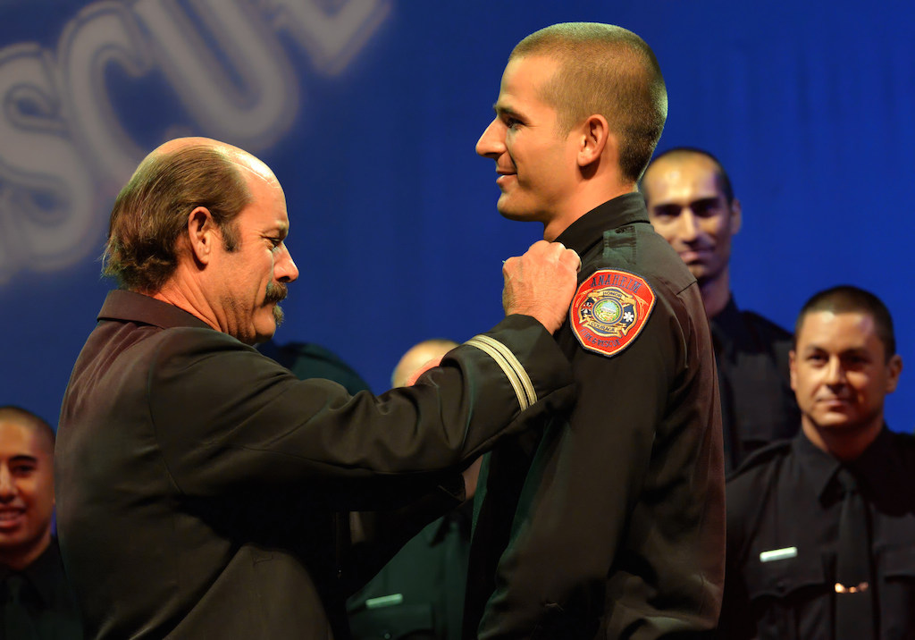 Anaheim Firefighter Tyler Bashaw receives his badge from his father, San Bernardino City Fire Capt. Sam Bashaw. Photo by Steven Georges/Behind the Badge OC