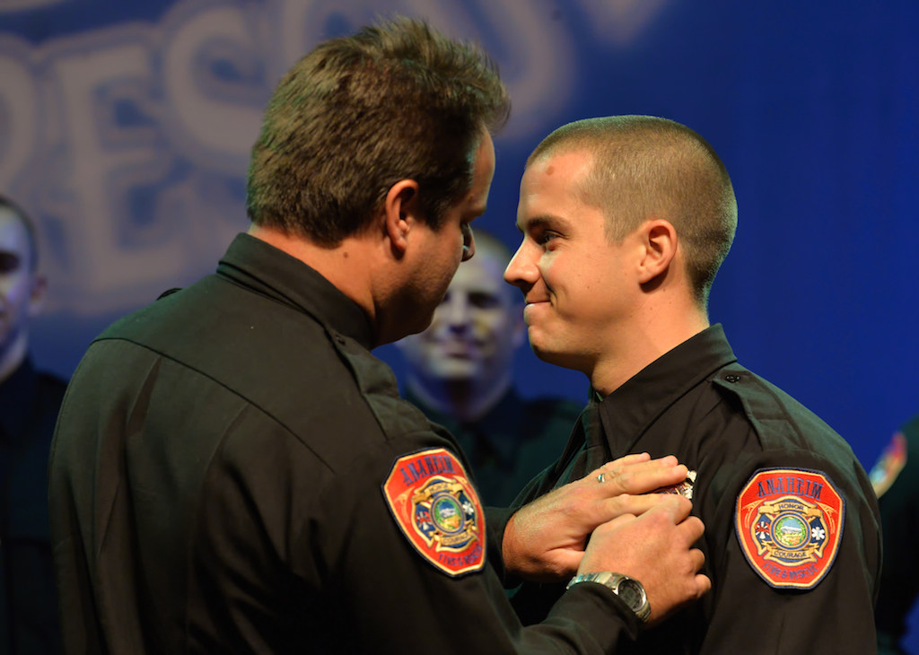 Anaheim Firefighter Jamison Bennett receives his badge from Anaheim Fire & Rescue Engineer Rob Tebbutt. Photo by Steven Georges/Behind the Badge OC